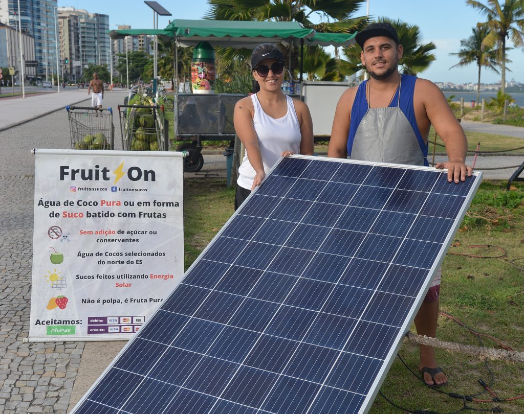 Simon e Juliana Belmok, vendedores de coco e suco na praia de Camburi, Vitória, que usam placa de energia solar para gerar energia. Foto: Chico Guedes