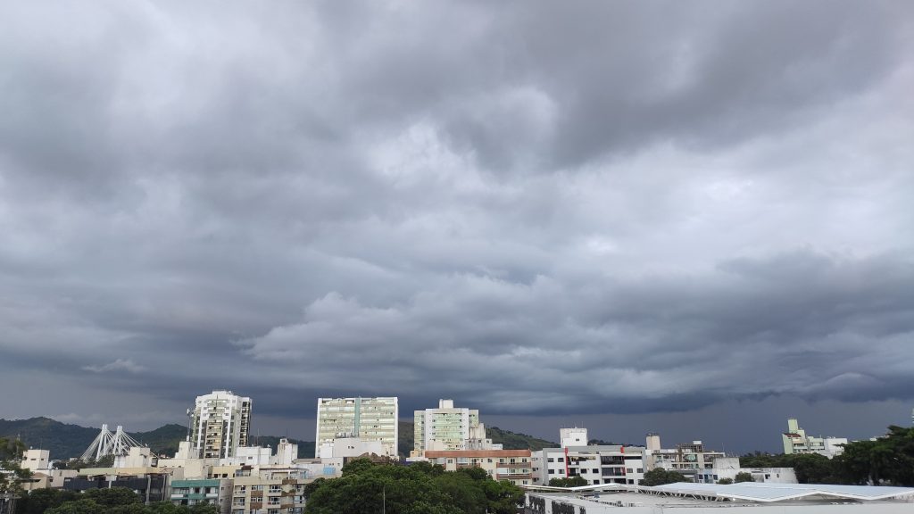 Céu nublado e tempo fechado indicando chuva para Vitória. Em baixo é possível ver muitos prédios e a Ponte da Passagem