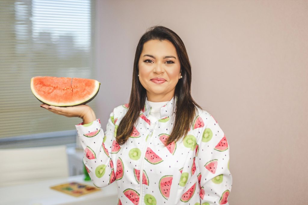 Nutricionista infantil Gláucia Cunha segurando uma melancia em uma das mãos.