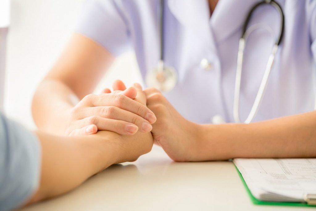 Médico atendendo paciente. Médico segura mão do paciente