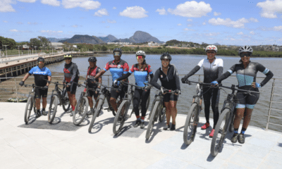 Ciclistas com suas bicicletas posando na nova orla de Cariacica, com o mar ao fundo