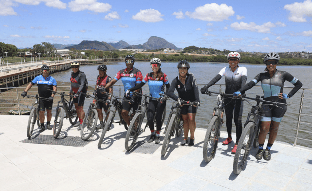 Ciclistas com suas bicicletas posando na nova orla de Cariacica, com o mar ao fundo