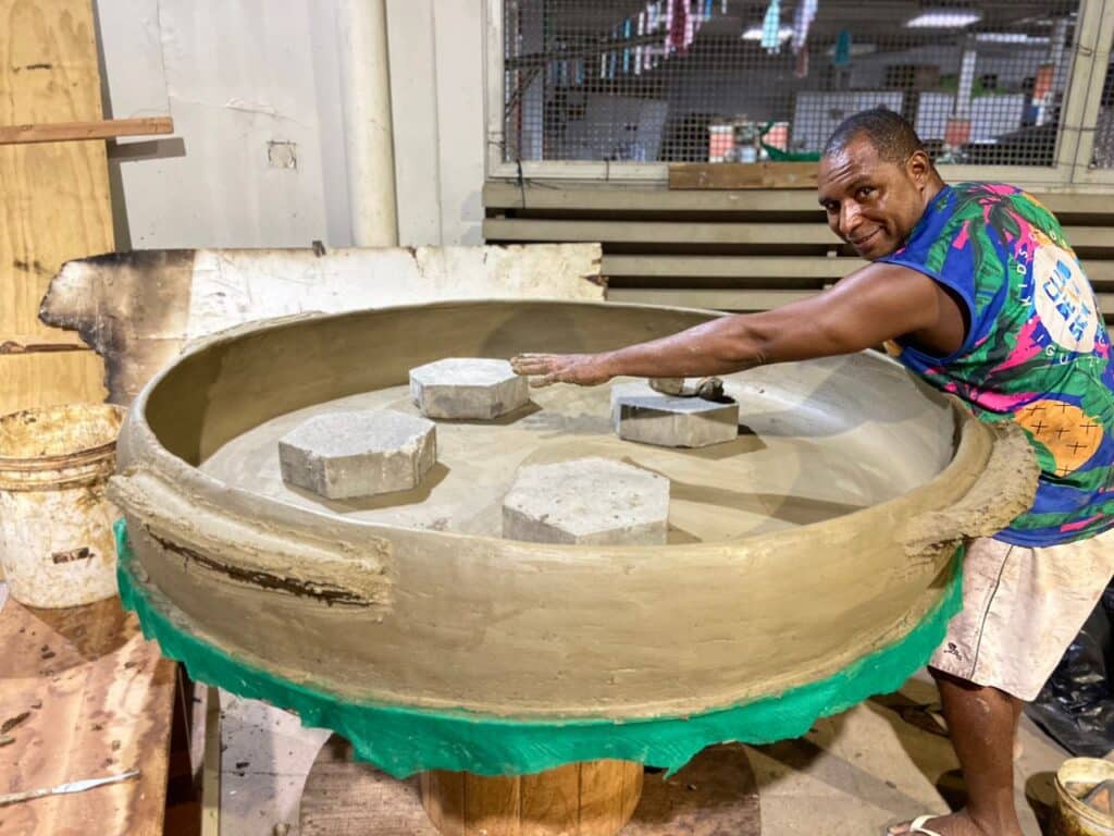 Flávio Fernandes Santos com uma panela de barro gigante de 1,50 metros. Ele mostra com o braço que a panela é grande