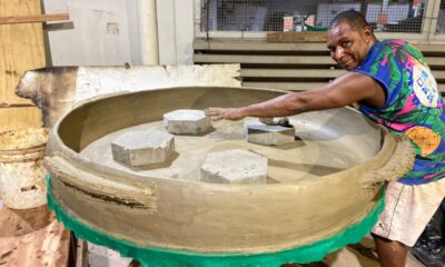 Flávio Fernandes Santos com uma panela de barro gigante de 1,50 metros. Ele mostra com o braço que a panela é grande