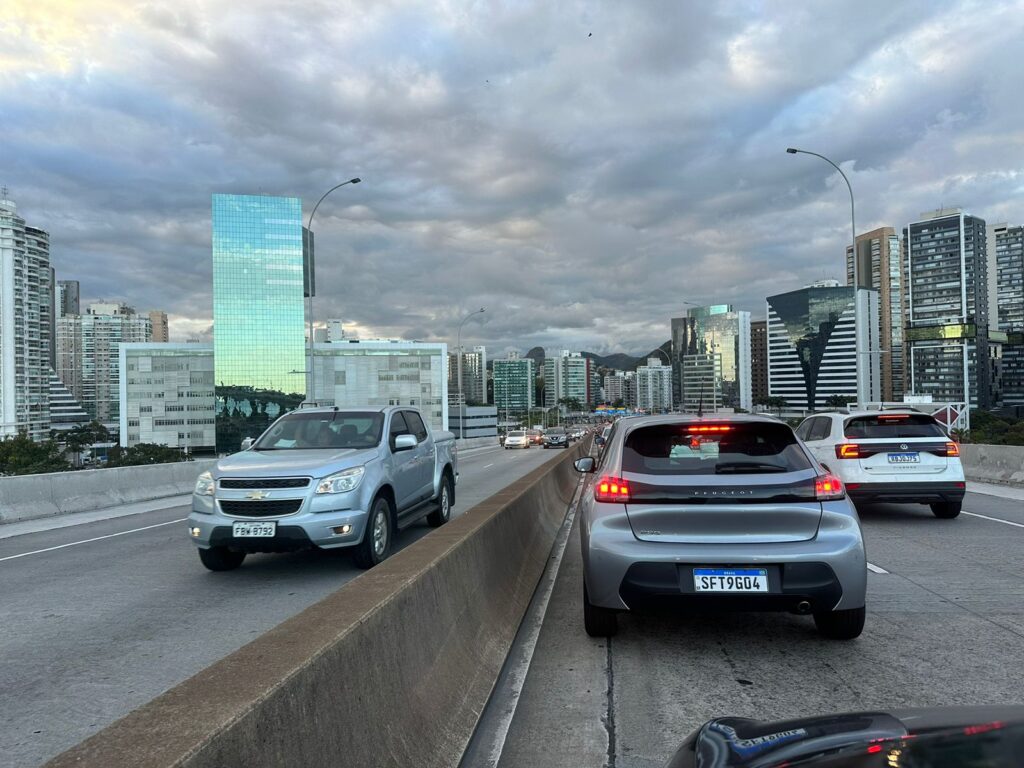 Carros nos dois sentidos da Terceira Ponte e muitas nuvens no céu.