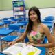 Amanda Teixeira Zampiris sentada na sala de aula na escola estadual com um livro na carteira.