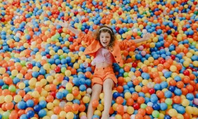 A brinquedolândia, que é uma piscina cheia de bolinhas coloridas e uma criança de roupa laranja se jogando