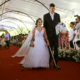 Paulla e Samuel vestidos de noivos no tapete vermelho do casamento comunitário da Serra