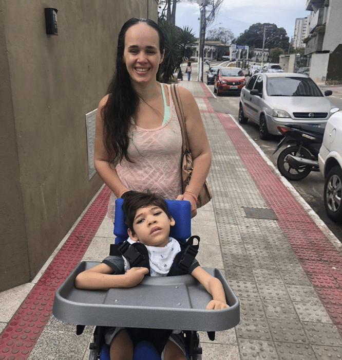 Fátima Marcarini é cega e mãe de Guilherme que tem microcefalia. Os dois passeiam pelas suas do bairro onde moram. O menino na cadeira de rodas.