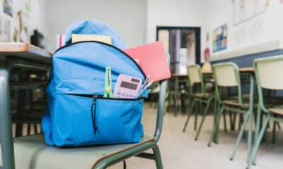 Campanha arrecada mochila de criança. A mochila azul com materiais escolar em cima de uma cadeira de sala de aula