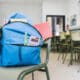 Campanha arrecada mochila de criança. A mochila azul com materiais escolar em cima de uma cadeira de sala de aula