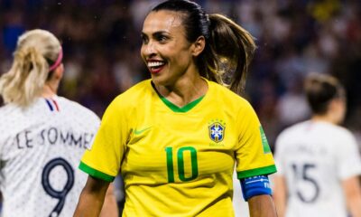 Na imagem uma mulher veste uma camisa verde e amarela da seleção brasileira