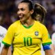 Na imagem uma mulher veste uma camisa verde e amarela da seleção brasileira