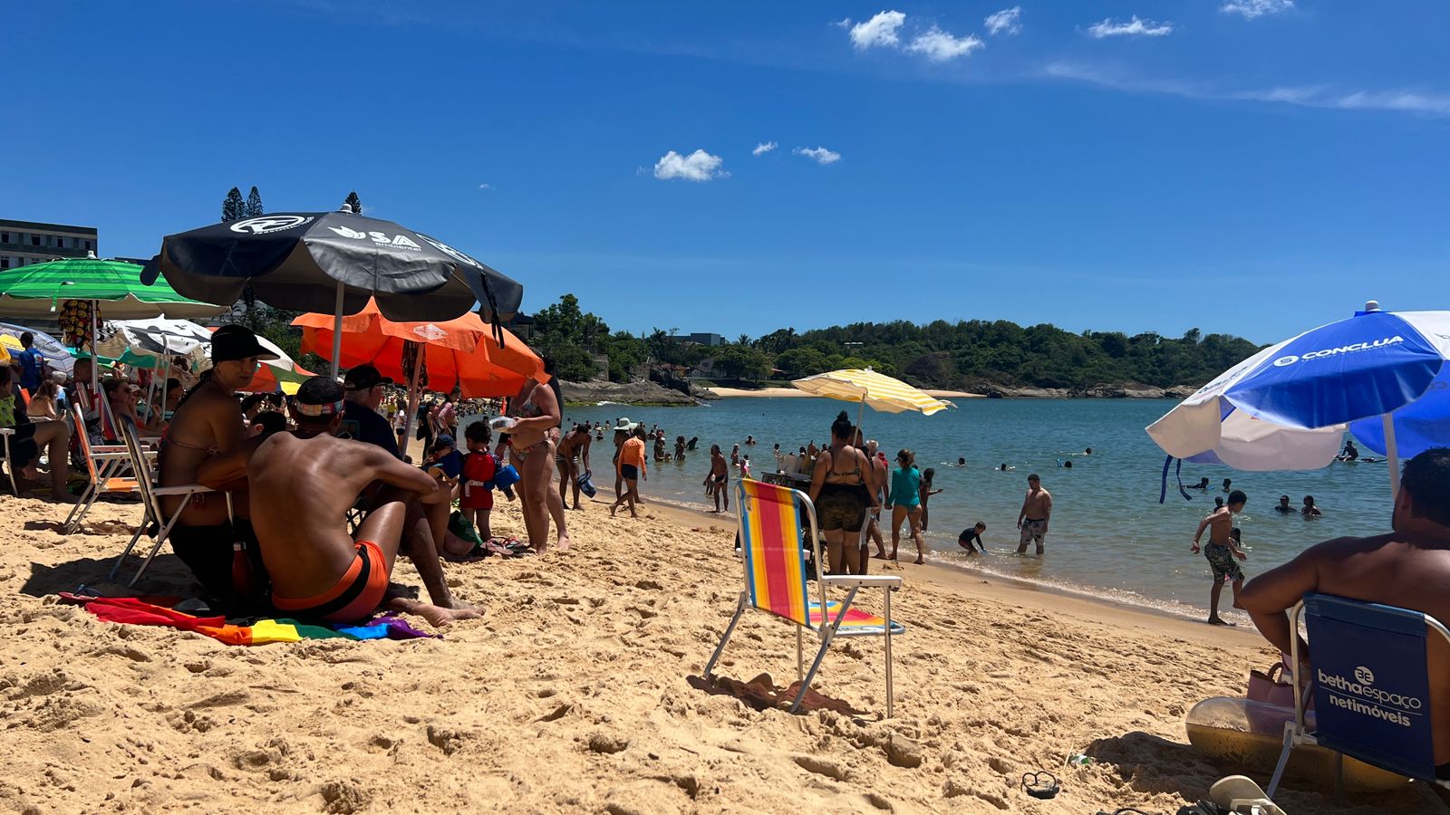 Praia da Costa cheia de banhistas em dia de sol e calor