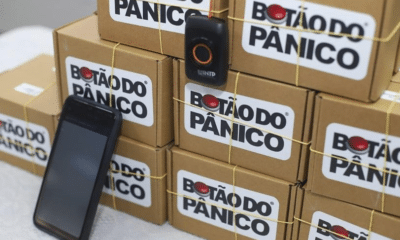 Celular e botão do pânicos em meio a caixas. Os dispositivos foram enviados para escolas da Serra