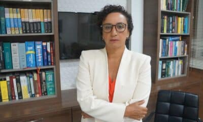 Érica Neves é diretora estadual da Associação Brasileira dos Advogados (ABA) posando pra foto em meio a livros e uma televisão ao fundo