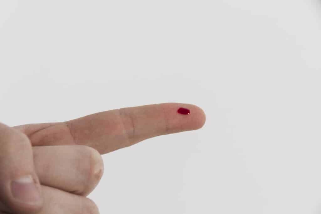 Dedo com uma gota de sangue para exame de dengue na farmácia