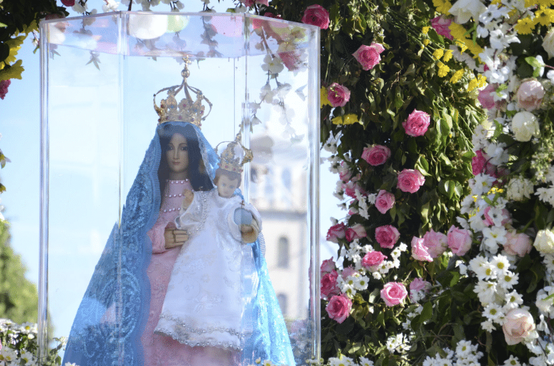 A imagem de Nossa Senhora da Penha em uma redoma de vidro envolta por um arco de flores
