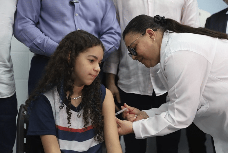 Uma enfermeira aplicando vacina contra dengue em uma pré-adolescente no Espírito Santo