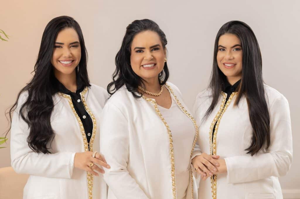 As especialistas em estética Vanessa Cabral e as suas filhas Gessica e Raquel Cabral posando juntas de jaleco branco para foto de divulgação