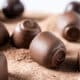 Bombons de chocolate espalhados em cima de uma mesa com cacau polvilhado. É para mostrar que a Apae de Vila Velha está pedindo doações para a Páscoa