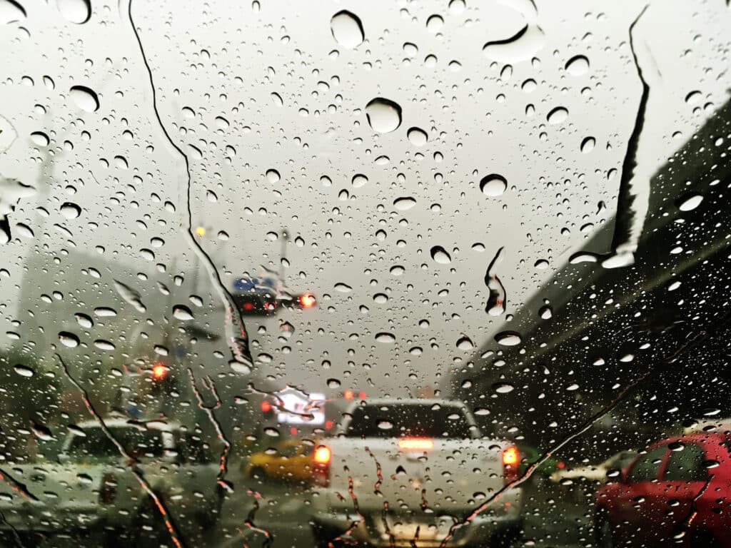 Chuvas intensas no parabrisa do carro e da pra ver outros carros no trânsito