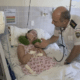 Na foto, Clarinha está deitada na cama do hospital, sendo acompanhada e observada pelo coronel Jorge Potratz