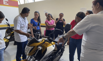 Muitas mulheres durante um curso de mecânica de motos. Um professor explicando