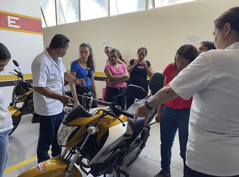 Muitas mulheres durante um curso de mecânica de motos. Um professor explicando