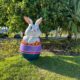 Um coelhinho saindo de um ovo colorido colocado em cima da grama. A ornamentação faz parte da Vila da Páscoa de Vitória, localizada na Praça dos Desejos