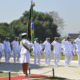 Oficiais da Marinha do Brasil enfileirados. Uma oficial com a bandeira do Brasil. Todos vestidos de branco. A Marinha do Brasil está com as inscrições abertas para concursos públicos