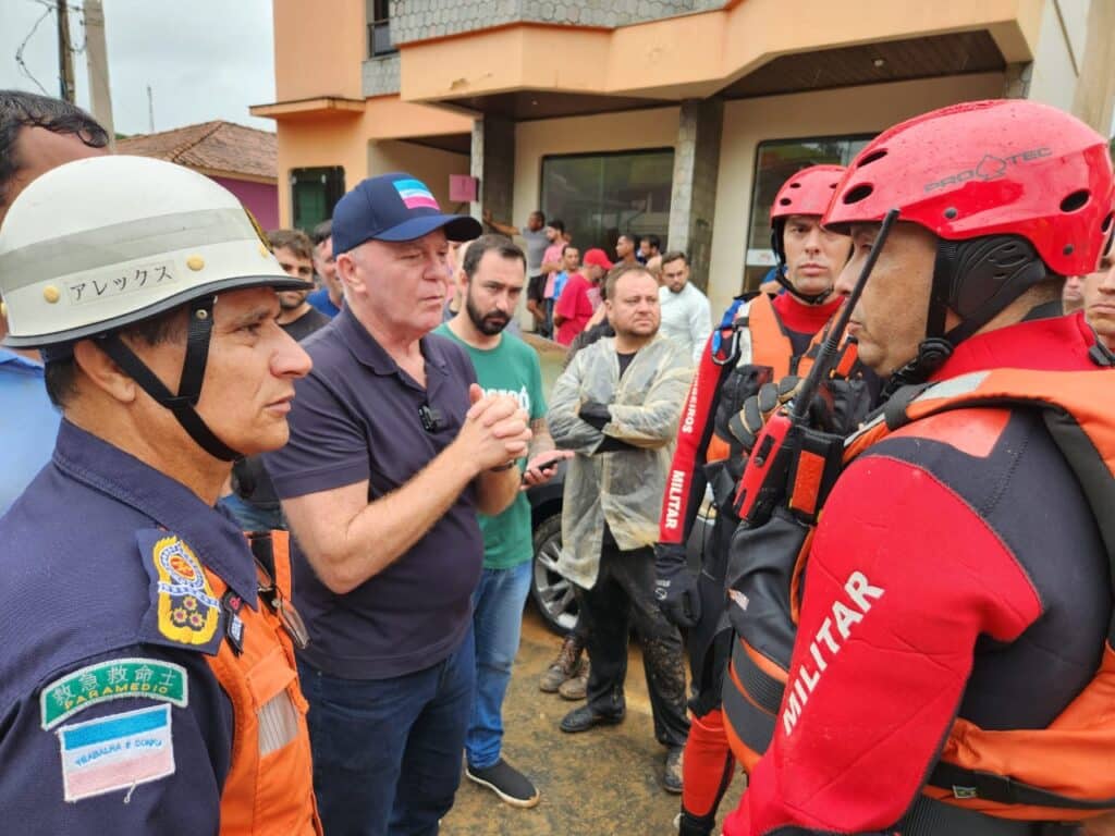 Renato Casagrande em conversa com bombeiros após chuvas fortes no Sul do Espírito Santo. É possível ver muitas pessoas ao redor do governador