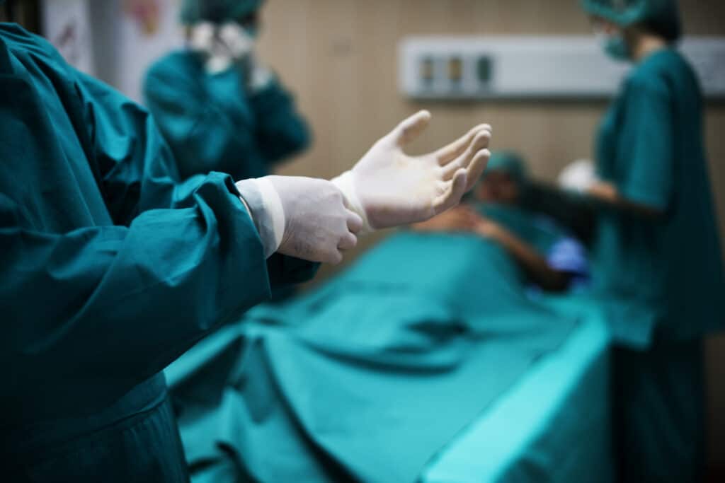 Um médico calçando a luva em uma sala de cirurgia bariátrica.