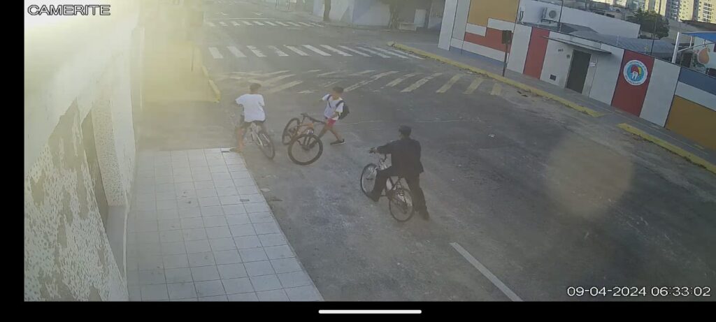 Na foto é possível ver quando um adolescente de bicicleta uniformizado é parado por dois indivíduos que também estão de bicicleta em Itapuã, Vila Velha