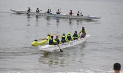 Praticantes de canoa havaiana remando em praia na arena de verão de Vitória