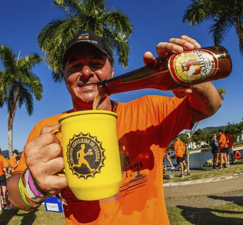 Um homem com a camisa do Circuito Cervejeiro de Corrida enchendo a caneca de cerveja