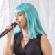 Menina de peruca azul cantando no microfone de cosplay representando a cultura geek