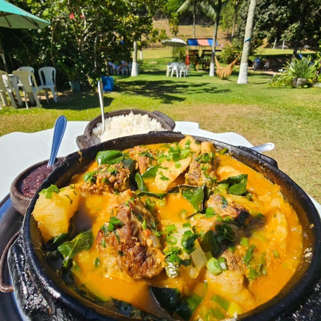 Uma comida servida na panela de barro com a Fazendinha JK, em Vila Velha, ao fundo