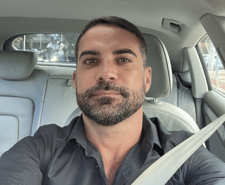 Médico Leandro Medice dentro de um casso com camisa de manga cinza posando pra foto