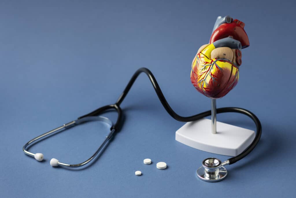 Um estetoscópio e uma reprodução de um coração com comprimidos. É para ilustrar matéria sobre colesterol