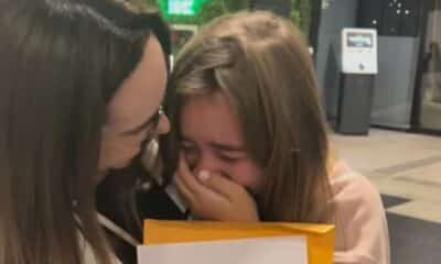 Joice Belisário faz surpresa no Aeroporto de Vitória para filha Maria Eduarda. As duas abraçadas com um papel na mão que indicava o destino da viagem