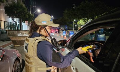 Uma agente de trânsito com bafômetro na mão na janela de um carro de um motorista