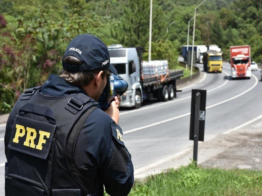 Agente da PRF usando radar móvel para fiscalização de velocidade na rodovia