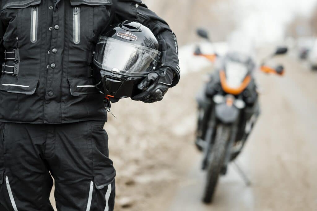 Mototaxistas parado em frente a moto com o capacete abraçado