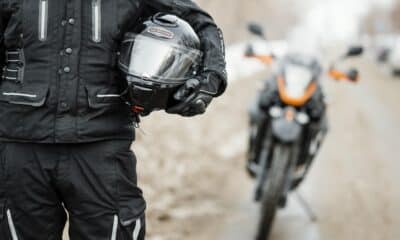 Mototaxistas parado em frente a moto com o capacete abraçado