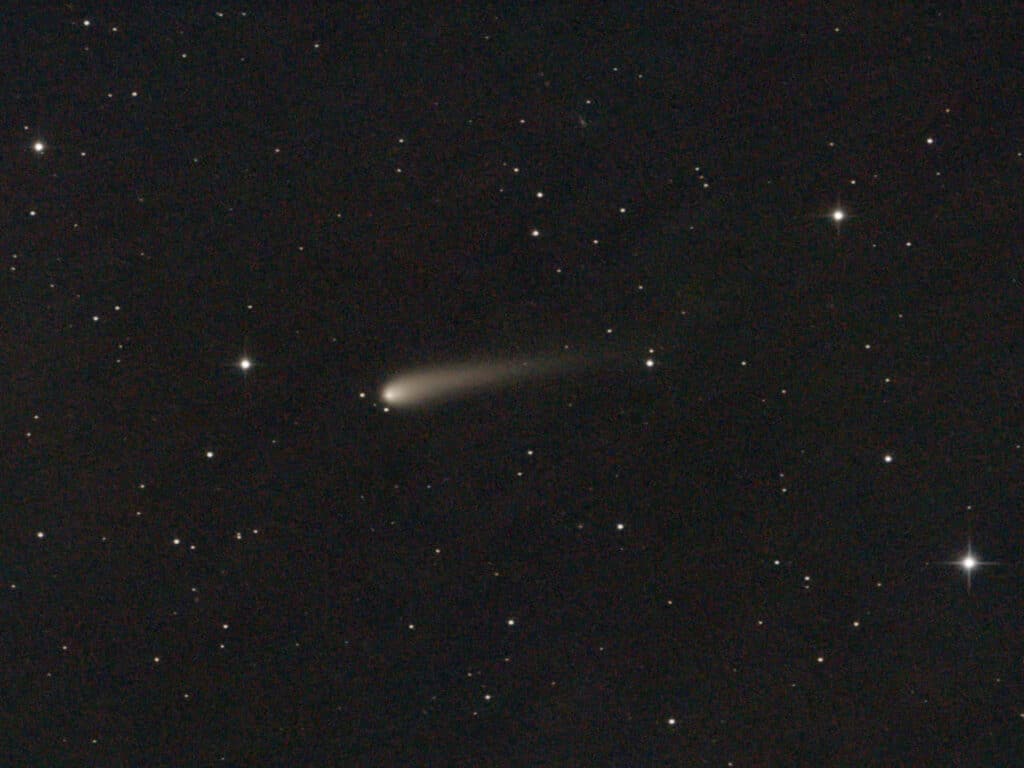 Detalhe de um cometa com uma cauda atravessando um céu estrelado