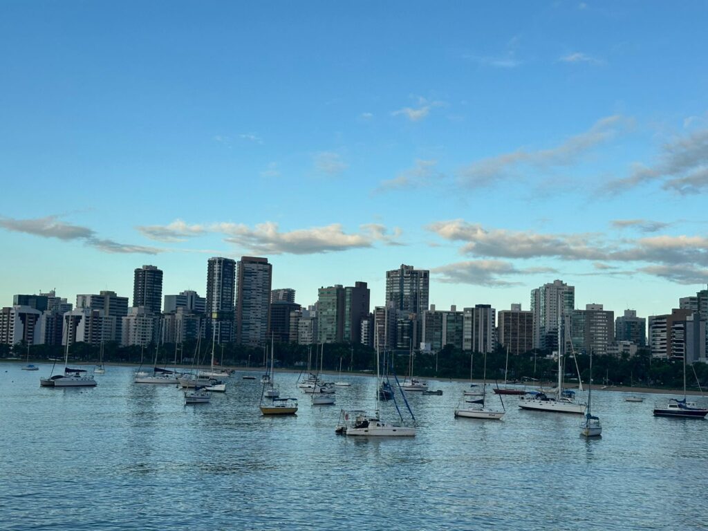 Dia de sol, prédios altos e barcos na baía de Vitória