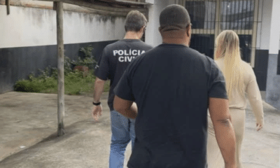 Suspeita é conduzida por policiais civis após ser flagrada com documento falso em frente a uma agência bancária em Marataízes