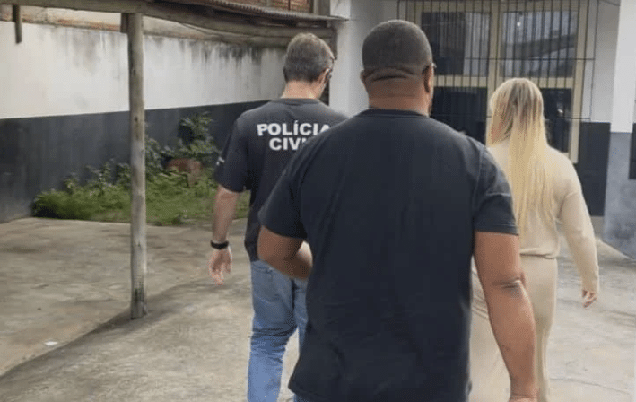 Suspeita é conduzida por policiais civis após ser flagrada com documento falso em frente a uma agência bancária em Marataízes