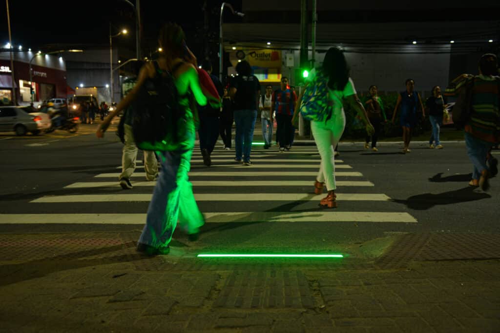 Pedestres atravessam faixa iluminada por barras de LED na Avenida Inteligente, em Laranjeiras, Serra